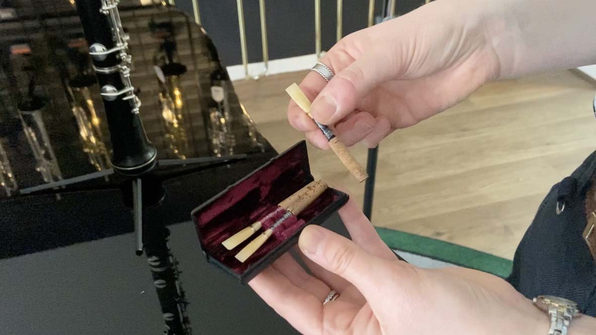1 oboe reed has been removed from reed case and is being held next to it.