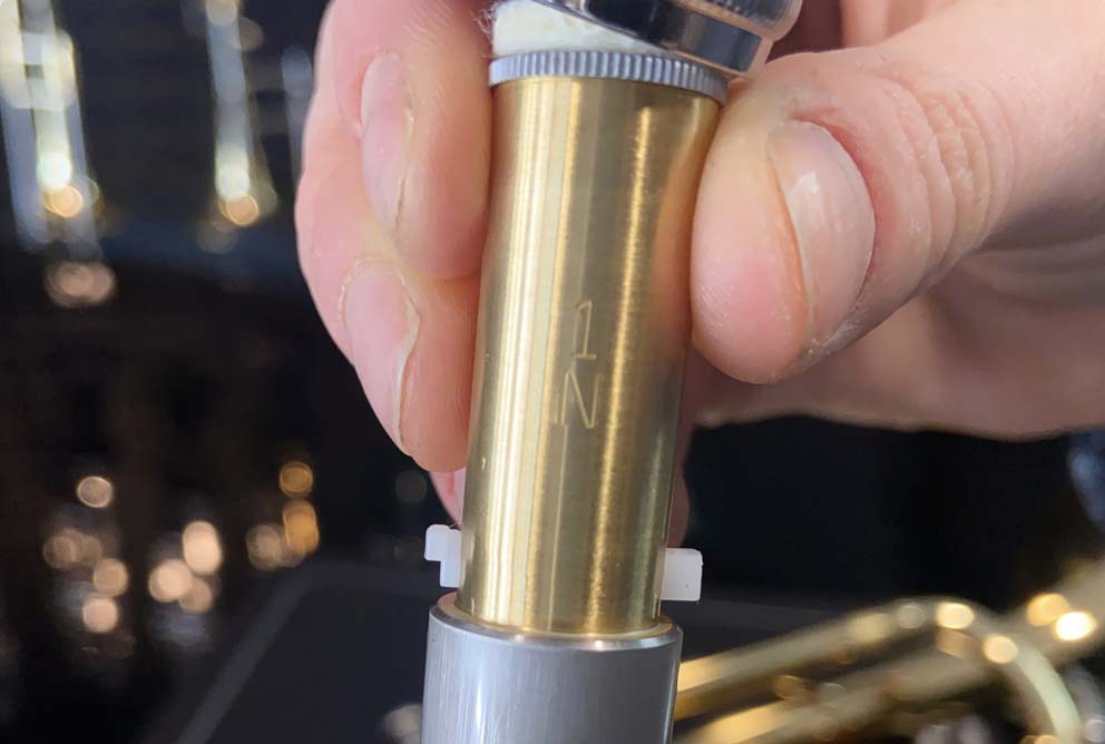 A trumpet valve is shown up close, showing the engraving of the number.